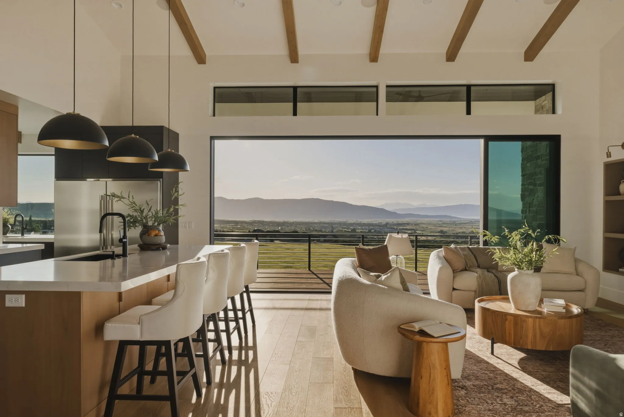 Open-concept living space featuring wood-finish flooring, exposed ceiling beams, and a full wall of glass sliders
