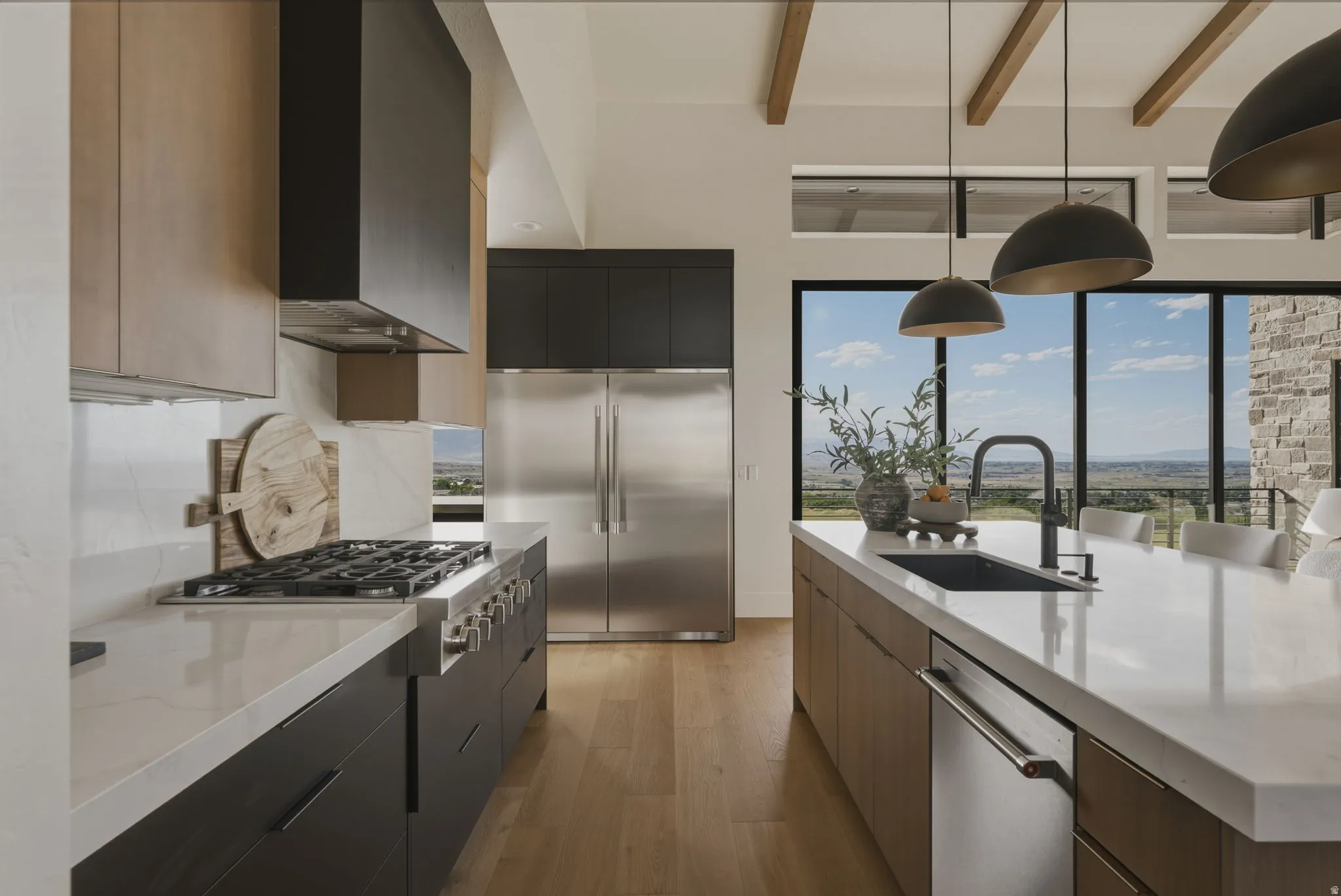 Modern kitchen featuring a gas range, large stainless steel refrigerator, white countertops, and wood-finish flooring