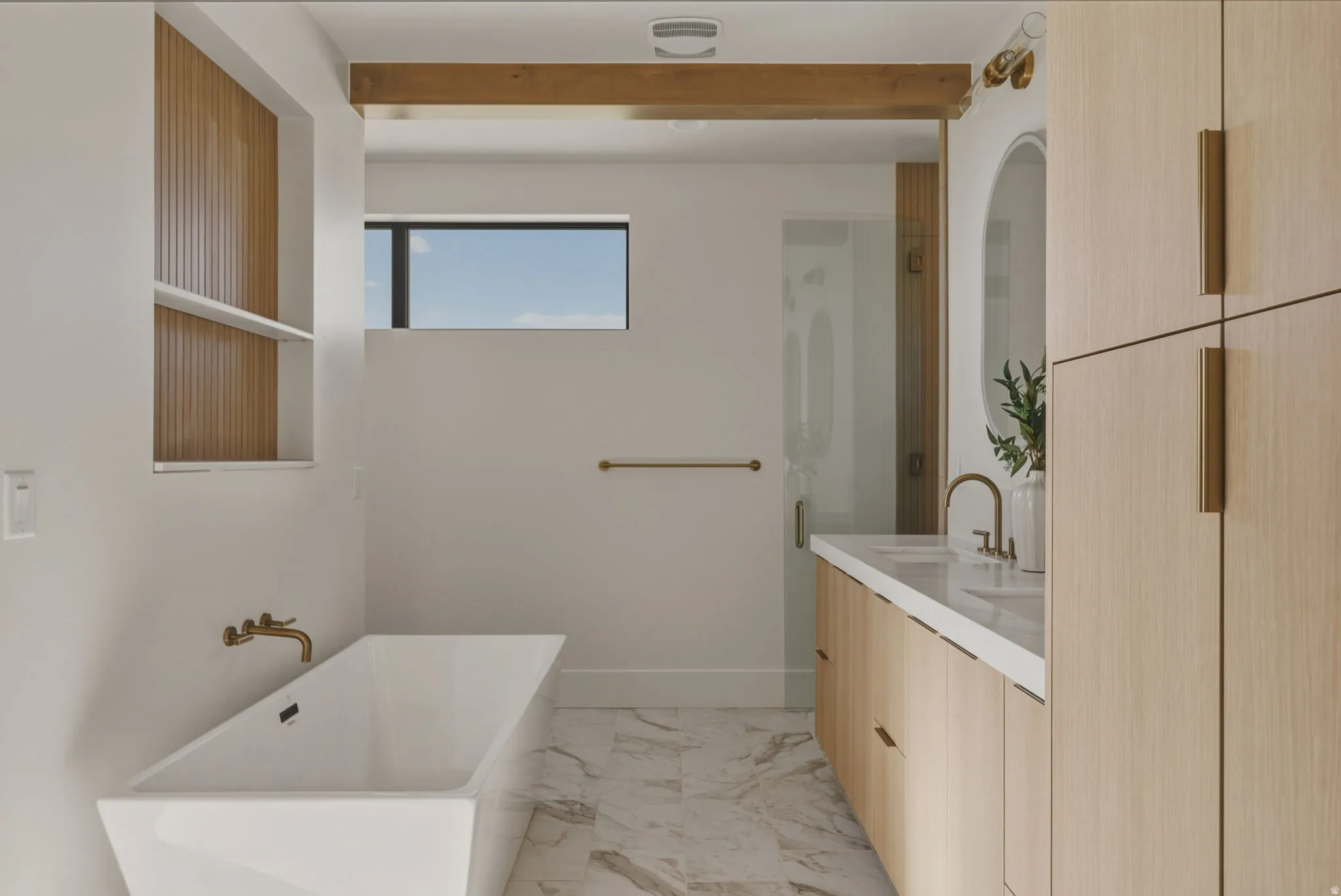Freestanding soaking tub with wall-mounted brass faucet