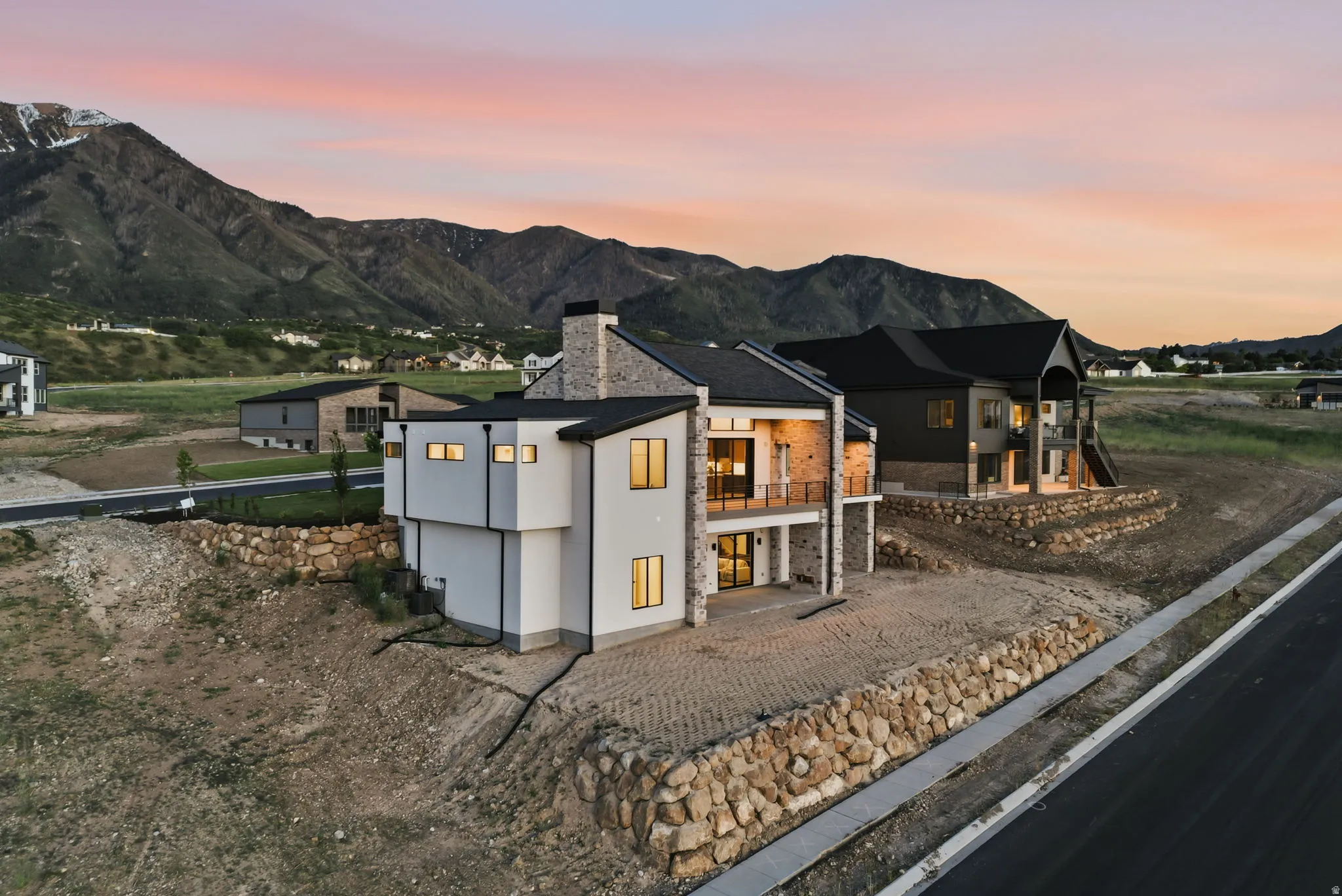 Contemporary architecture featuring a multi-level design, stone facade accents, dark framed windows, and a prominent balcony