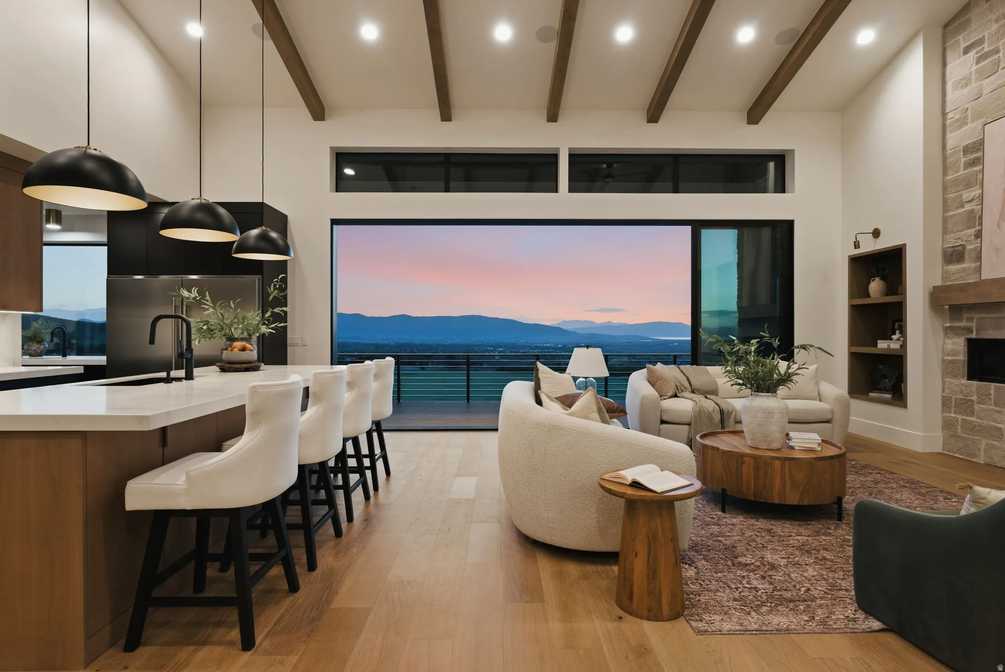 Open-concept living space with large format sliding glass doors, exposed ceiling beams, a stone fireplace with a wood mantle, an integrated kitchen island with a double basin sink, and wood-finish flooring