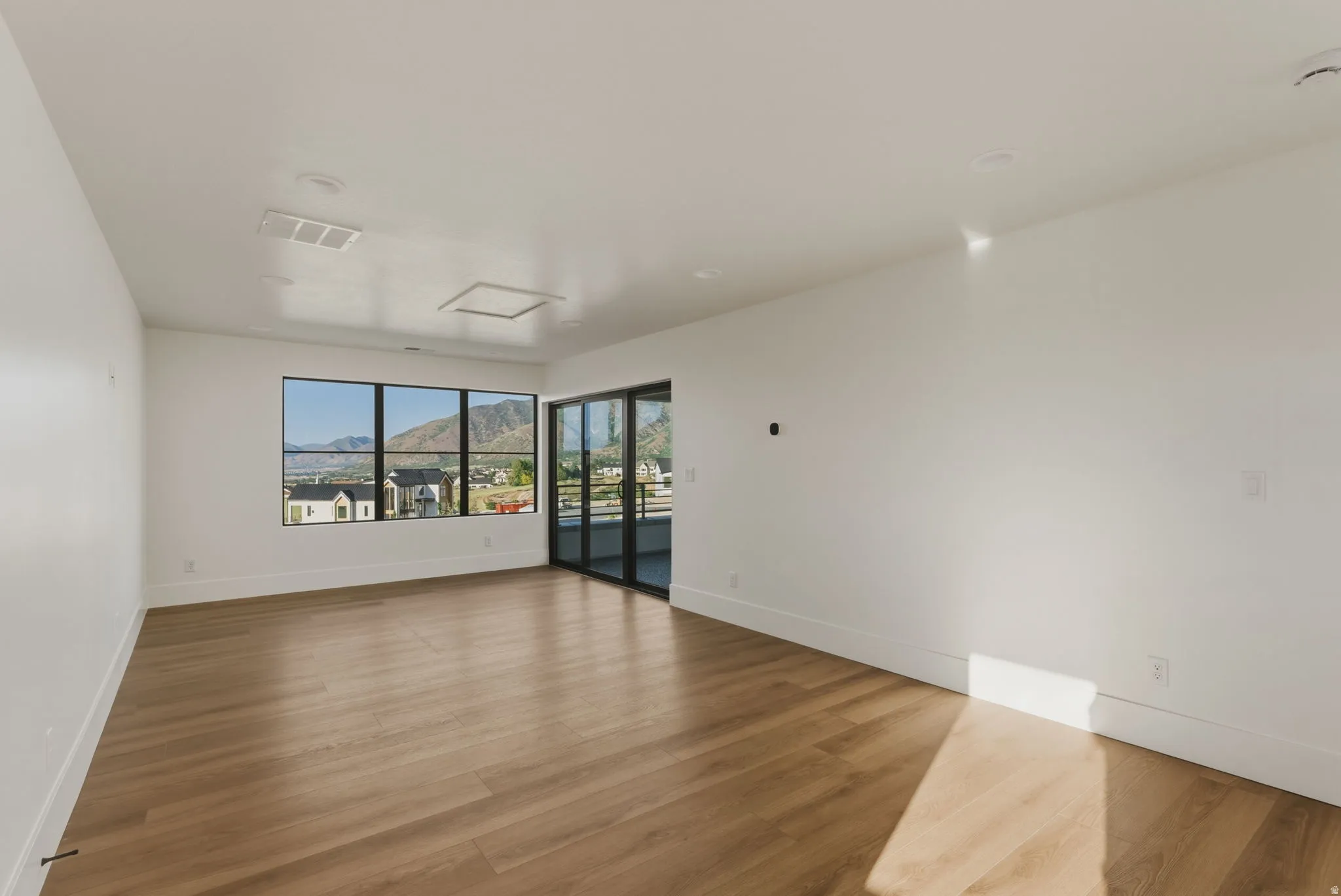 Spacious interior room featuring expansive windows with mountain and neighborhood scenery