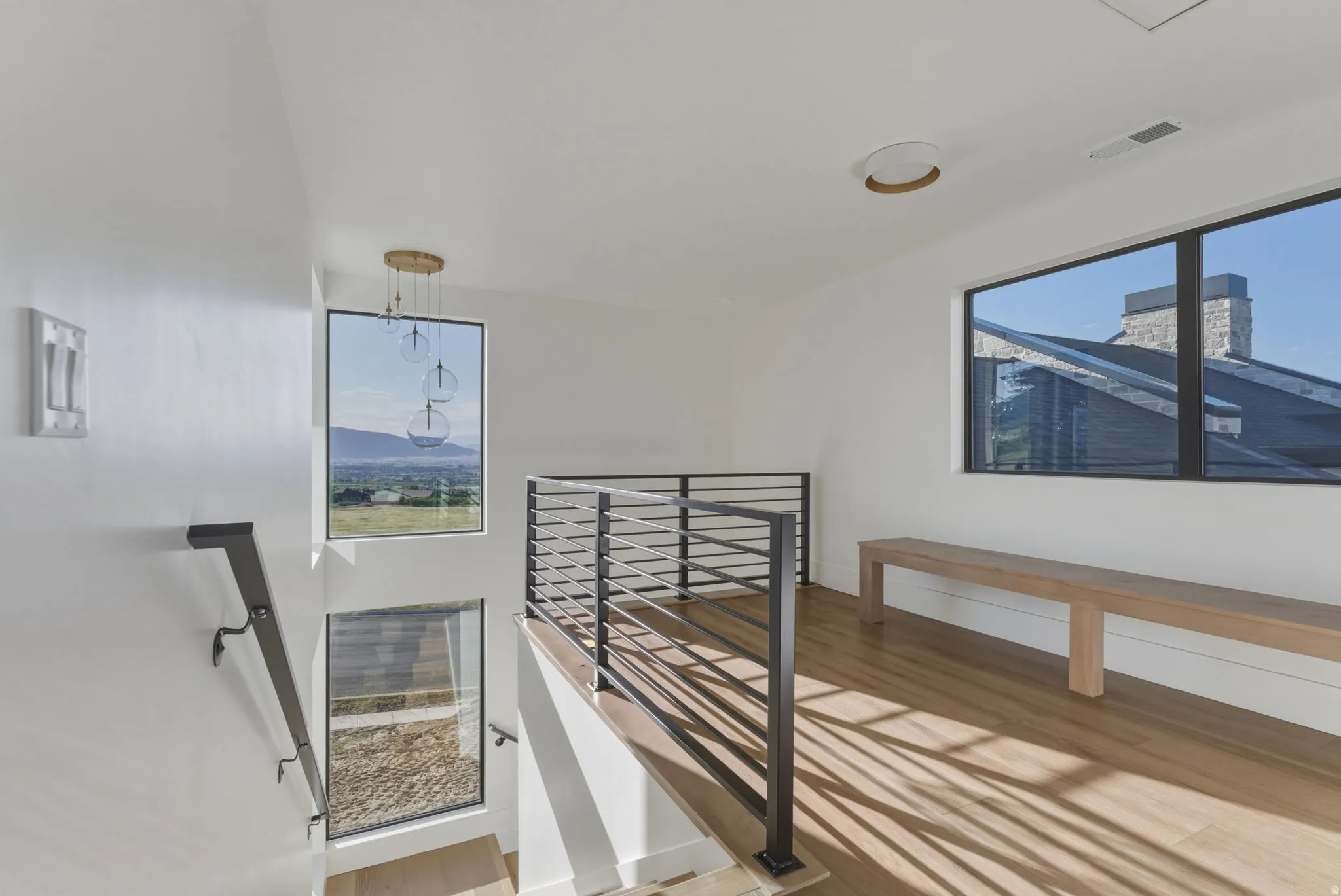 Upper landing featuring light wood-finish flooring, white walls, and a modern horizontal railing