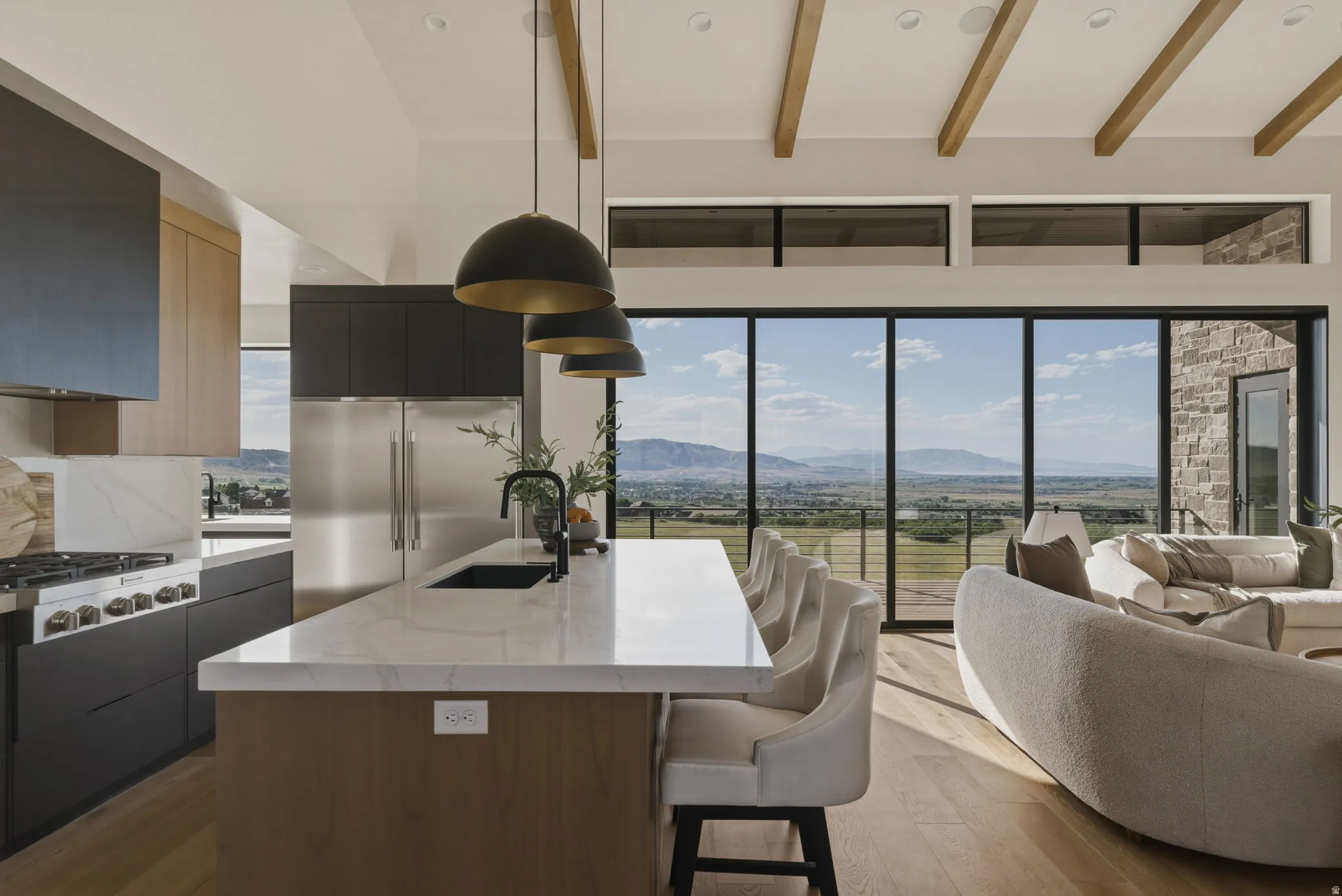 Contemporary kitchen featuring a large central island with seating, stainless steel appliances, and contrasting dark and wood-finish cabinetry