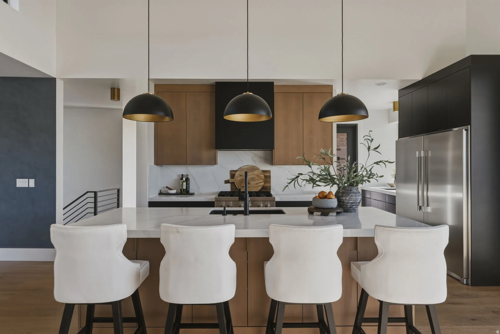 Gourmet kitchen featuring a substantial island with stone countertop, stainless steel appliances, dark cabinetry, and wood-finish flooring