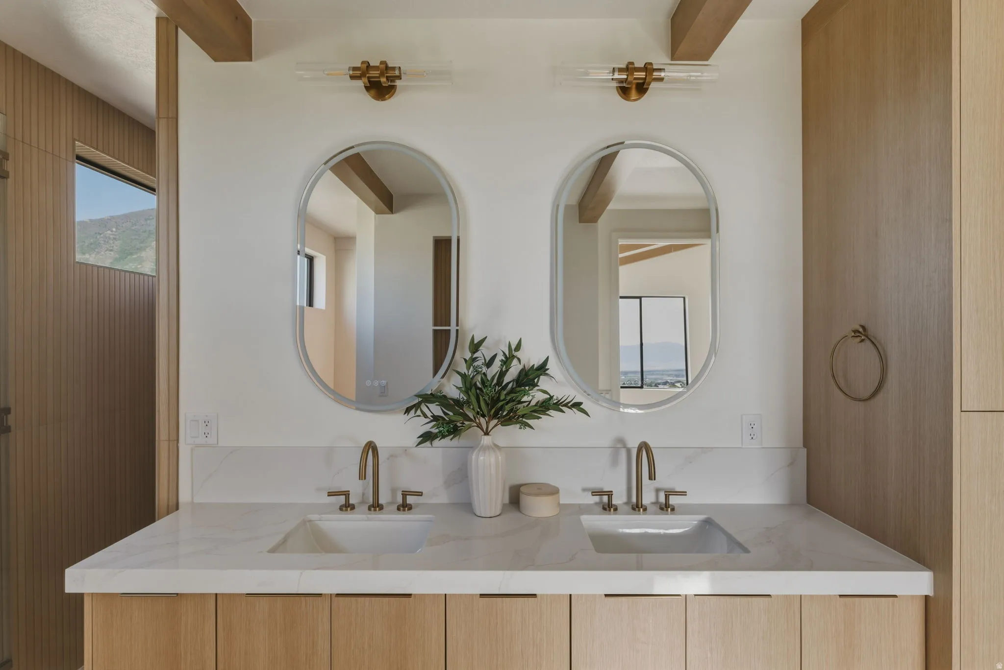 Dual vanity featuring undermount sinks, bronze faucets, and a light-toned countertop