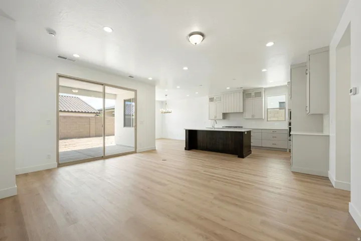 Spacious open-concept living area featuring light wood-finish flooring, recessed lighting, and a modern kitchen