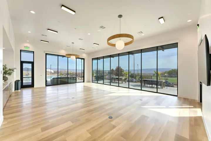 Expansive interior space featuring large format wood-finish flooring, floor-to-ceiling windows, two contemporary circular pendant lights, and recessed ceiling lighting