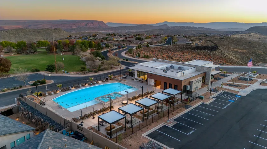 Expansive outdoor pool with integrated spa, bordered by a modern clubhouse featuring a flat roof and stone accents
