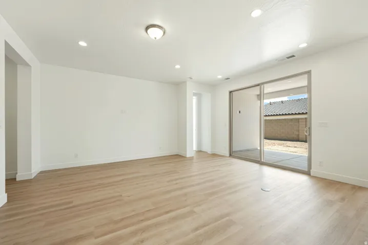 Spacious room with light wood-finish flooring and bright white walls