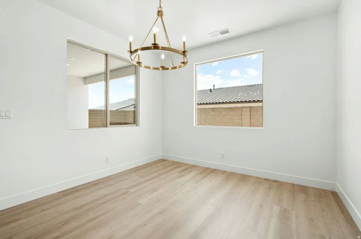Open concept interior featuring wide plank wood-finish flooring, a contemporary brass chandelier, and white baseboards