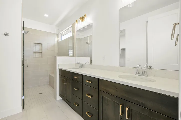 Bathroom featuring a dark wood double vanity with gold hardware, light countertop, and dual sinks