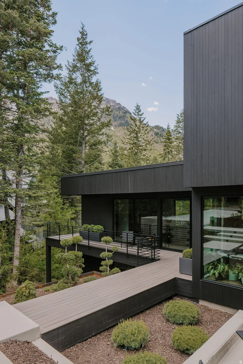 Modern exterior featuring dark vertical siding and a multi-level deck