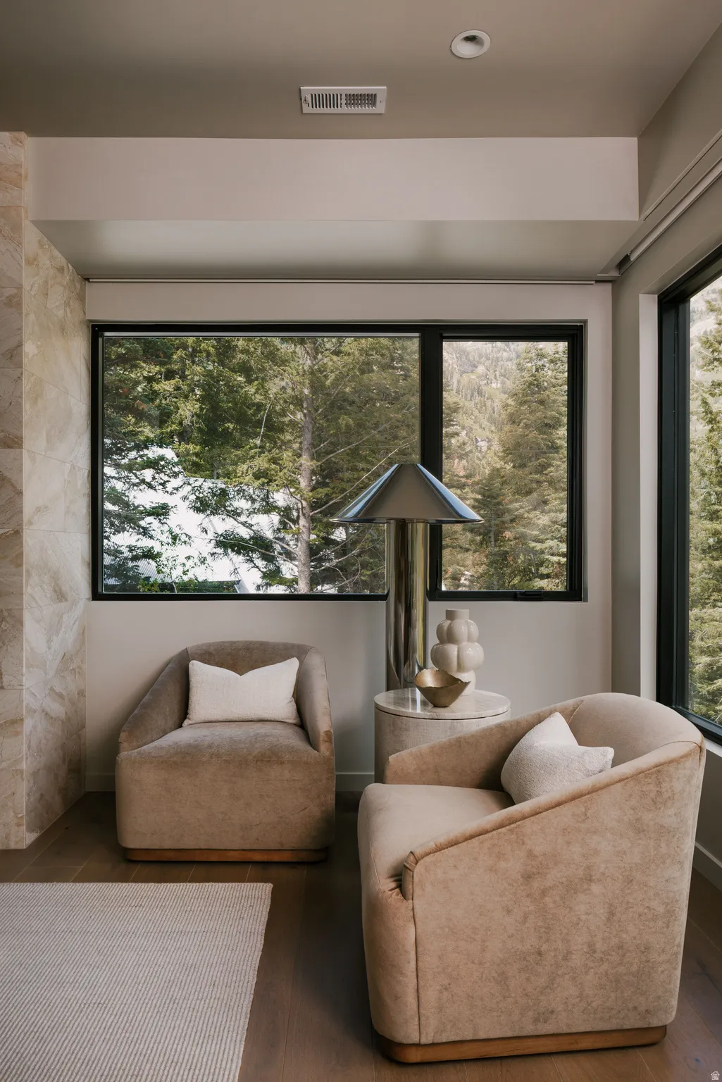 Large black-framed windows with a forest backdrop