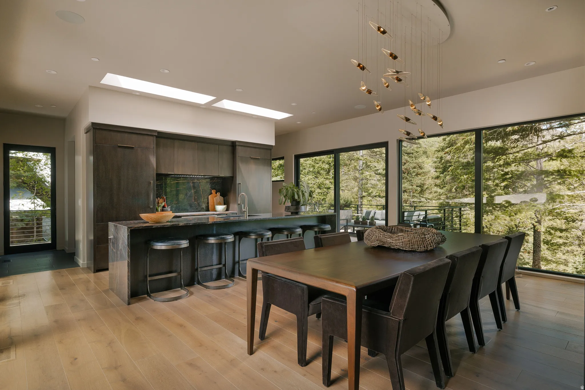 Open-concept living space featuring wood-finish flooring, a contemporary kitchen island with a built-in sink, and full-height windows