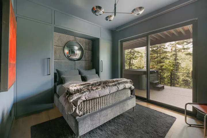 Bedroom featuring built-in cabinetry, wood-finish flooring, a contemporary chandelier, and a sliding glass door opening to an outdoor deck