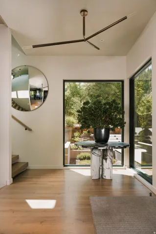 Entryway featuring wood-finish flooring, a contemporary chandelier, and a prominent floor-to-ceiling window showcasing exterior landscaping