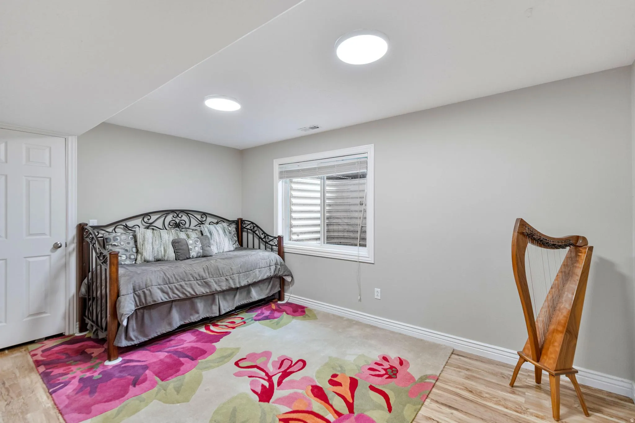 Recessed lighting illuminates a space featuring light wood-finish flooring and a white six-panel door