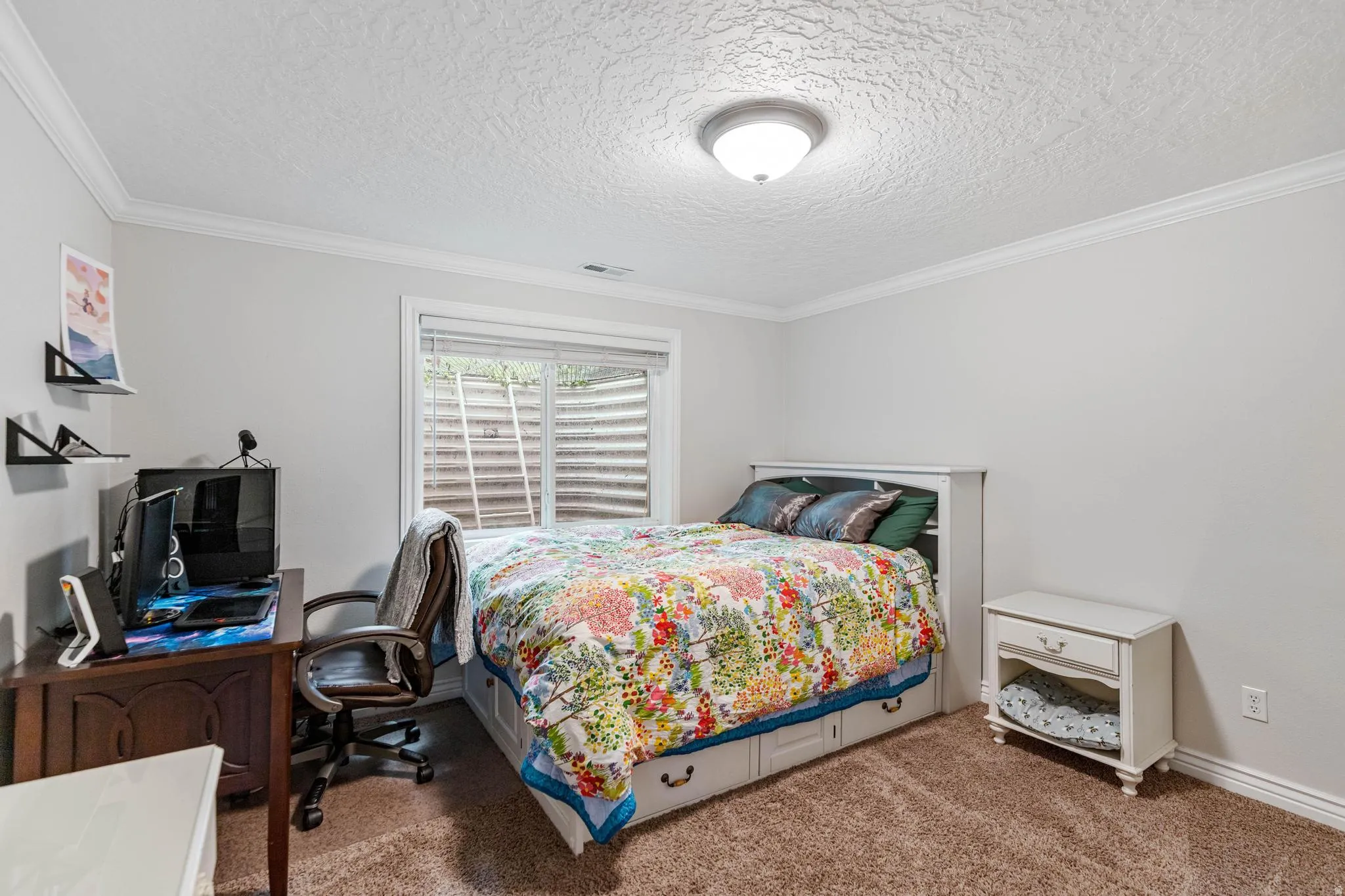 Spacious room featuring neutral wall tones, crown molding, a built-in window well, and plush carpeting
