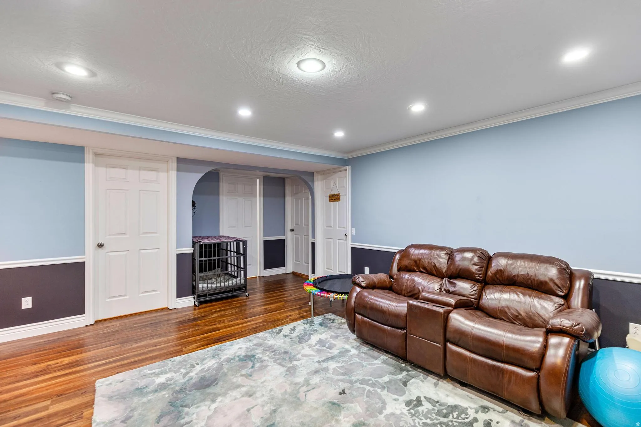 Spacious recreational room featuring wood-finish flooring, recessed lighting, and a two-tone wall treatment with crown molding