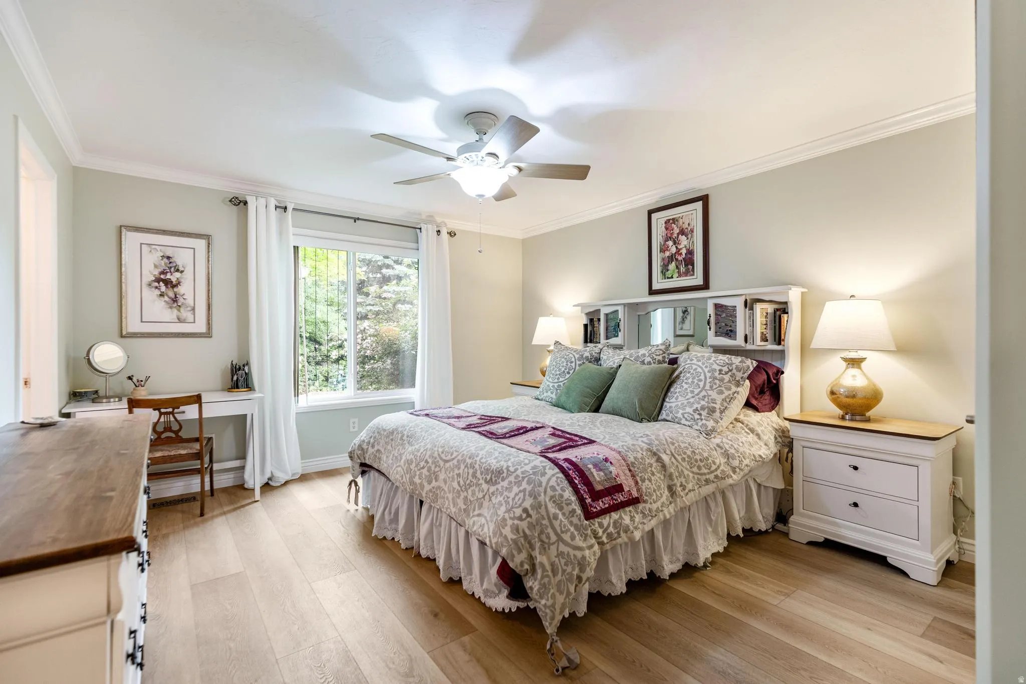 Spacious room featuring light wood-finish flooring, a large window, a ceiling fan, and crown molding