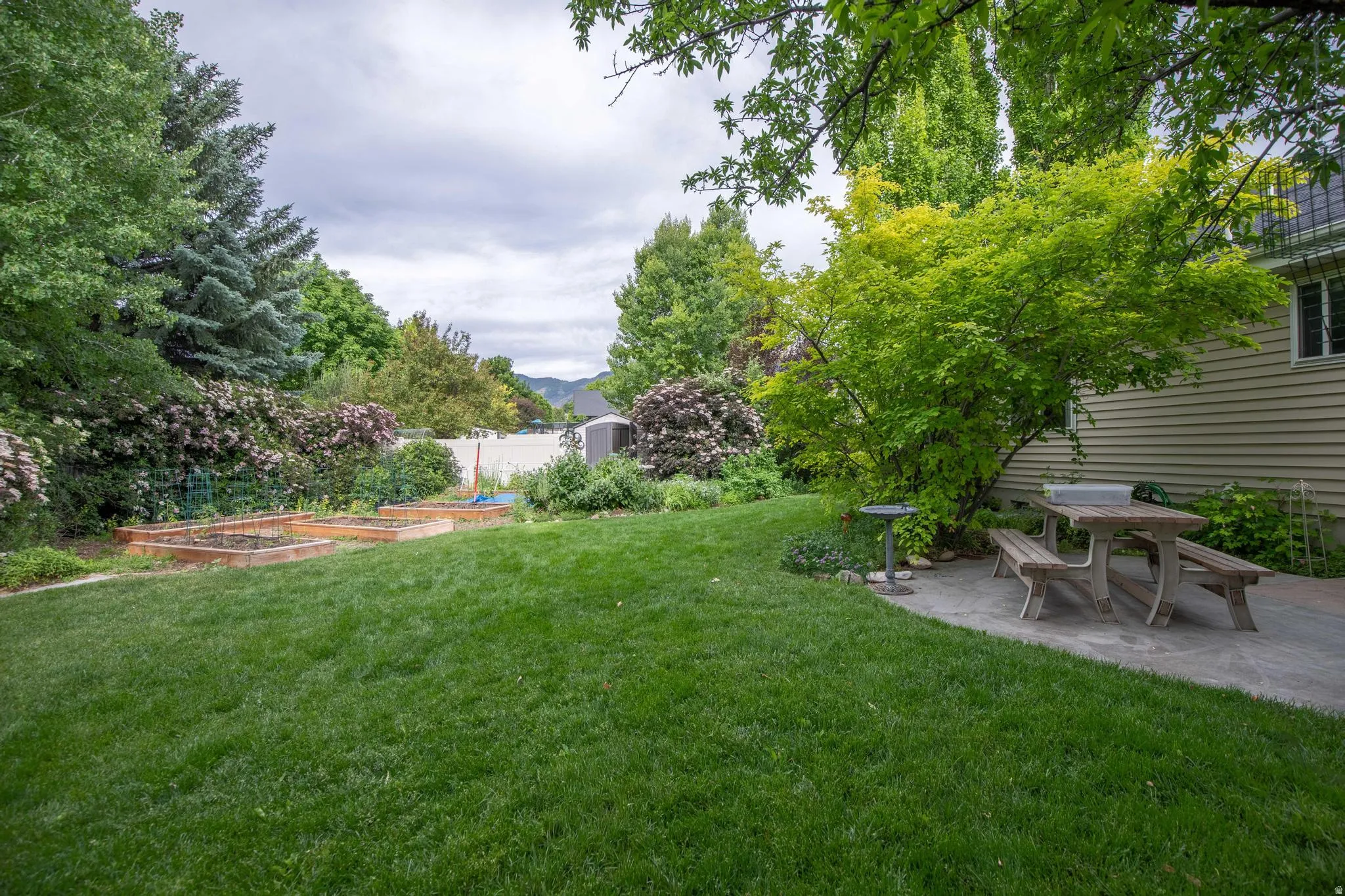 Spacious lawn with raised garden beds and a stone patio