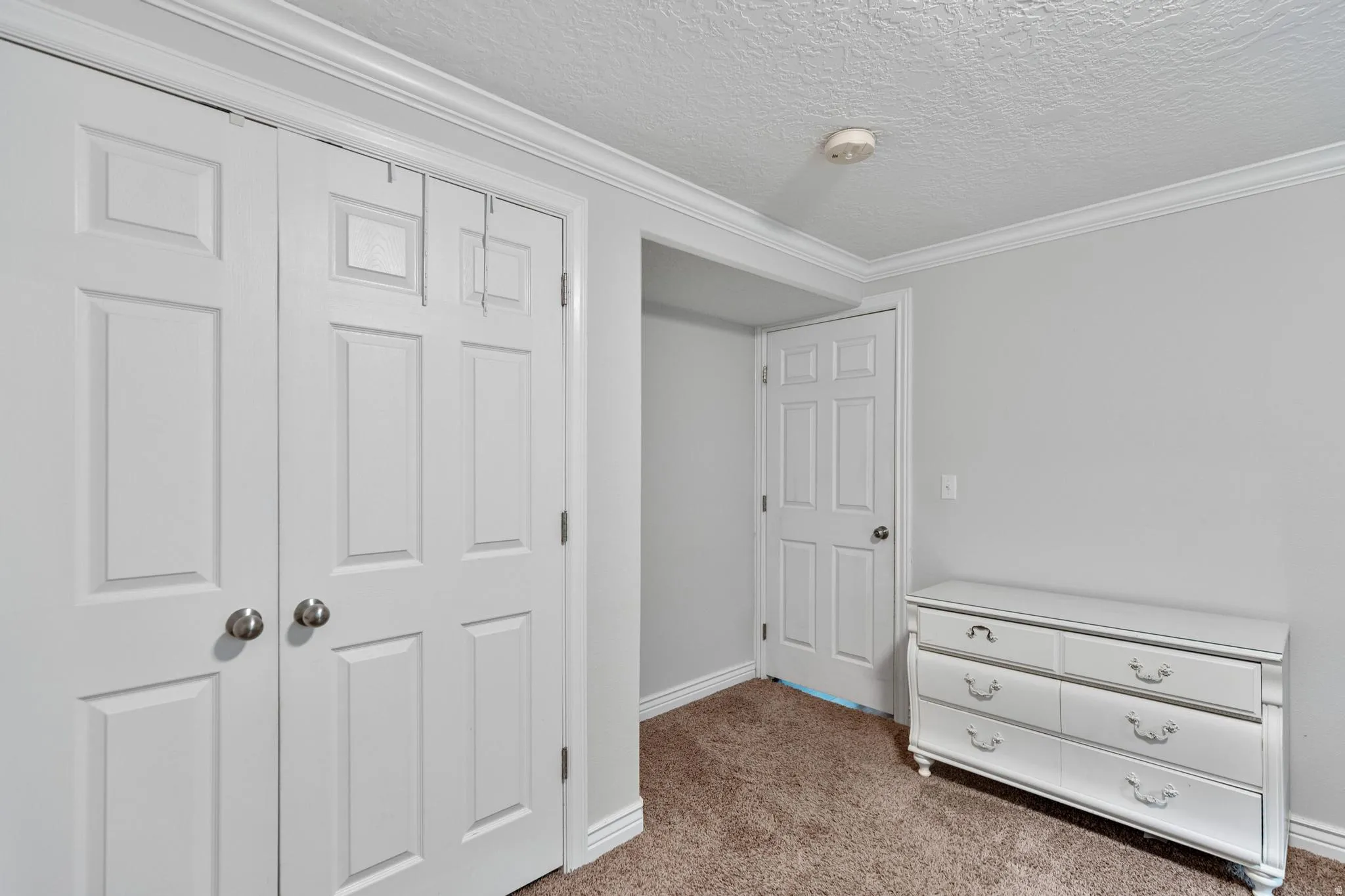 Room featuring a textured ceiling, neutral wall paint, and brown carpet flooring