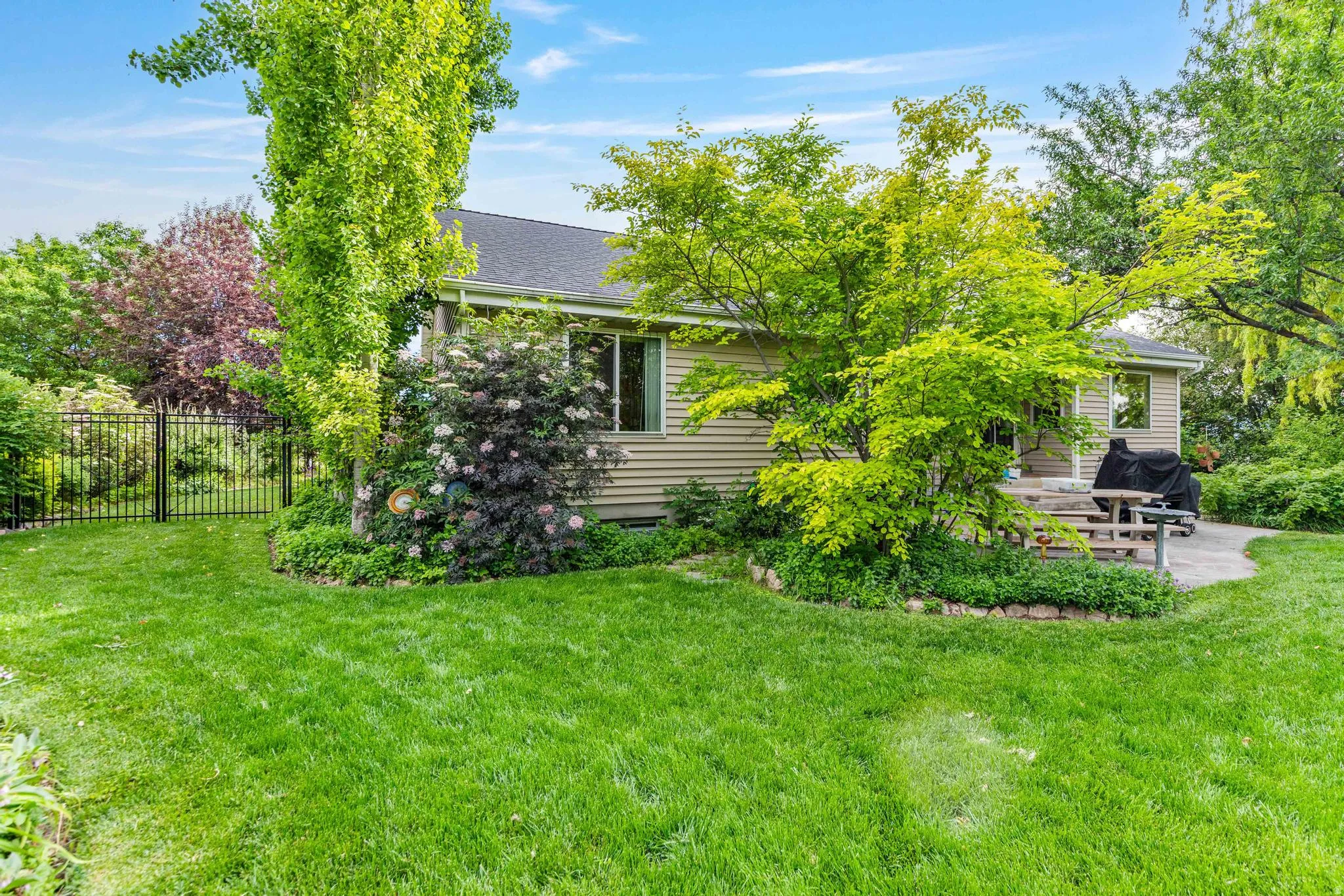 Spacious rear yard with expansive lawn, mature landscaping, and a stone patio