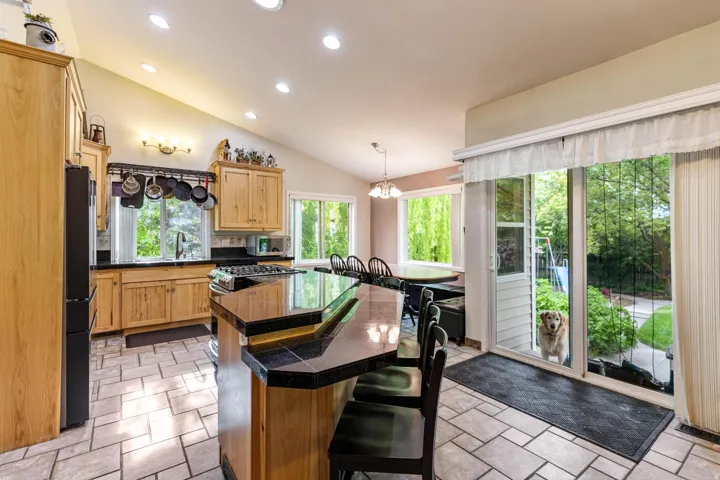 Kitchen featuring a multi-level island with seating, natural wood cabinetry, and recessed lighting