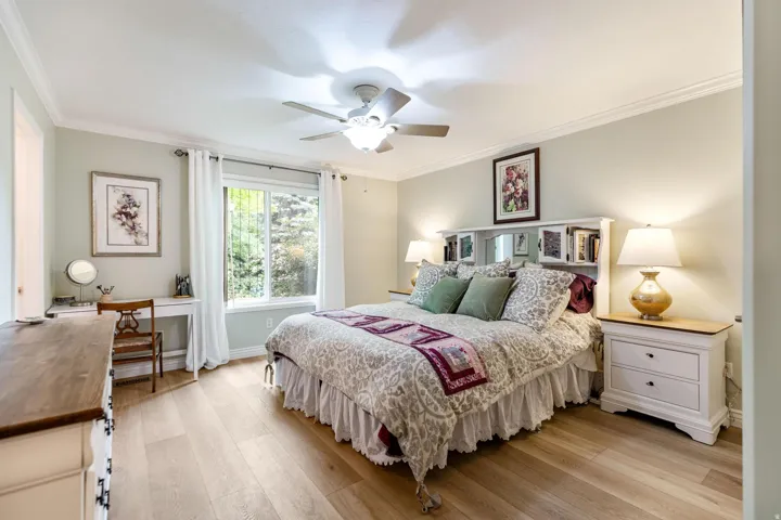 Spacious room featuring light wood-finish flooring, a large window, a ceiling fan, and crown molding