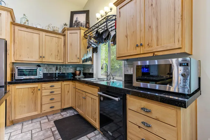 Kitchen featuring light wood cabinetry, dark speckled countertops, and a tile floor