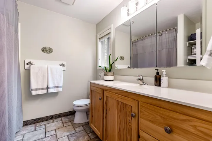 Bathroom featuring a light wood-finish vanity with a white countertop and integrated sink, chrome faucet, and three mirrored medicine cabinets