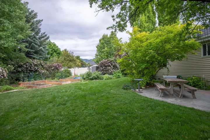 Spacious lawn with raised garden beds and a stone patio