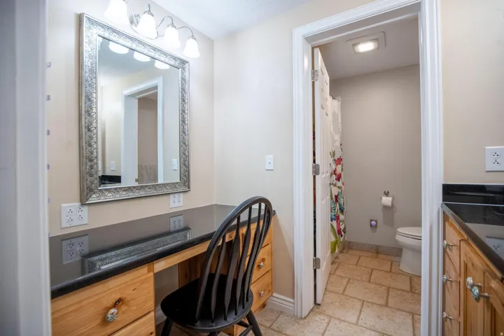 Vanity area featuring a large framed mirror, four-light fixture, wood-finish cabinetry, and dark countertop