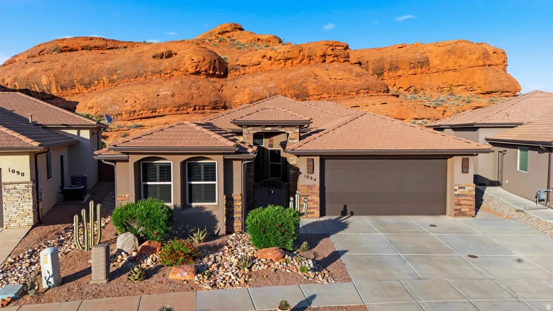 Southwestern-style residence featuring a tile roof, stucco and stone-veneer exterior, and an attached two-car garage