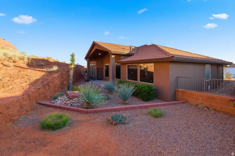 Southwestern-style exterior with a low-pitch tile roof, stucco siding, and multiple large windows