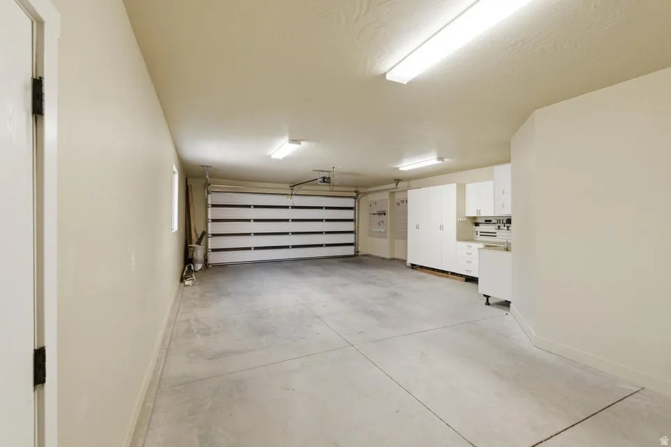 Spacious garage featuring a concrete floor, overhead fluorescent lighting, and white built-in cabinetry