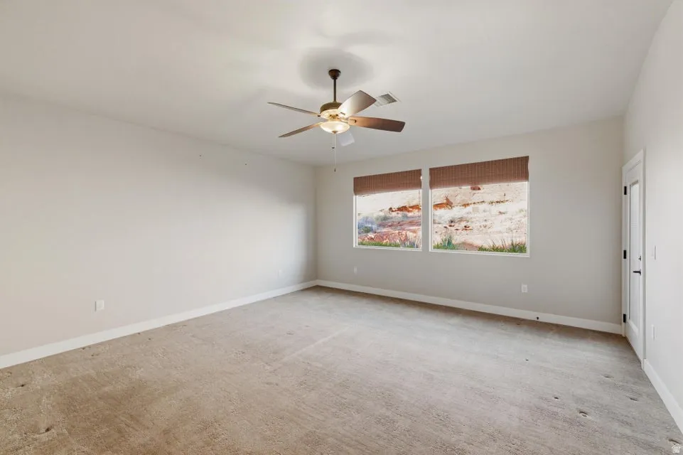 Spacious room with neutral carpet, light-toned walls, and a ceiling fan