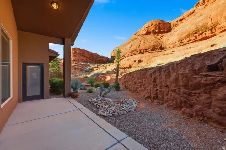 Covered patio with an exterior light fixture, concrete flooring, and a desert-themed landscape