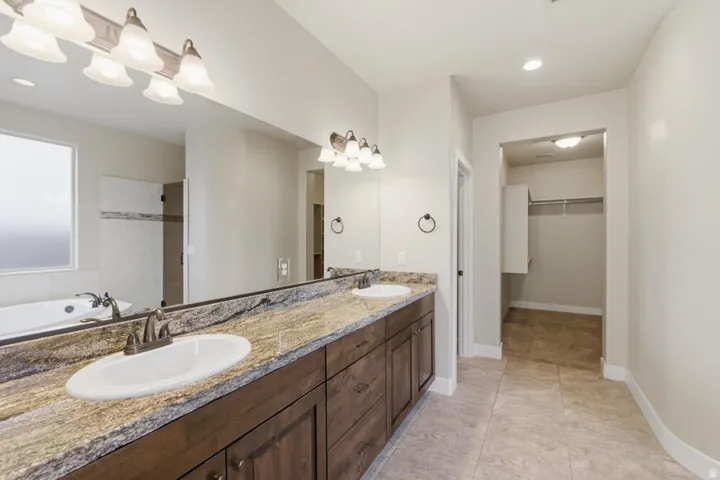 Double vanity with integrated sinks, rich wood cabinetry, and a broad stone countertop