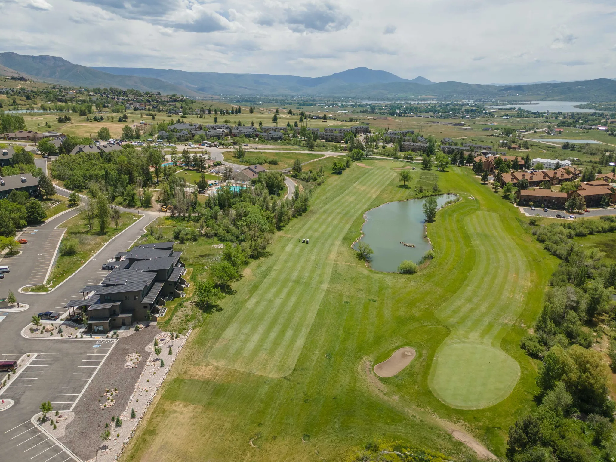 Expansive golf course setting featuring a green, sand trap, and water hazard