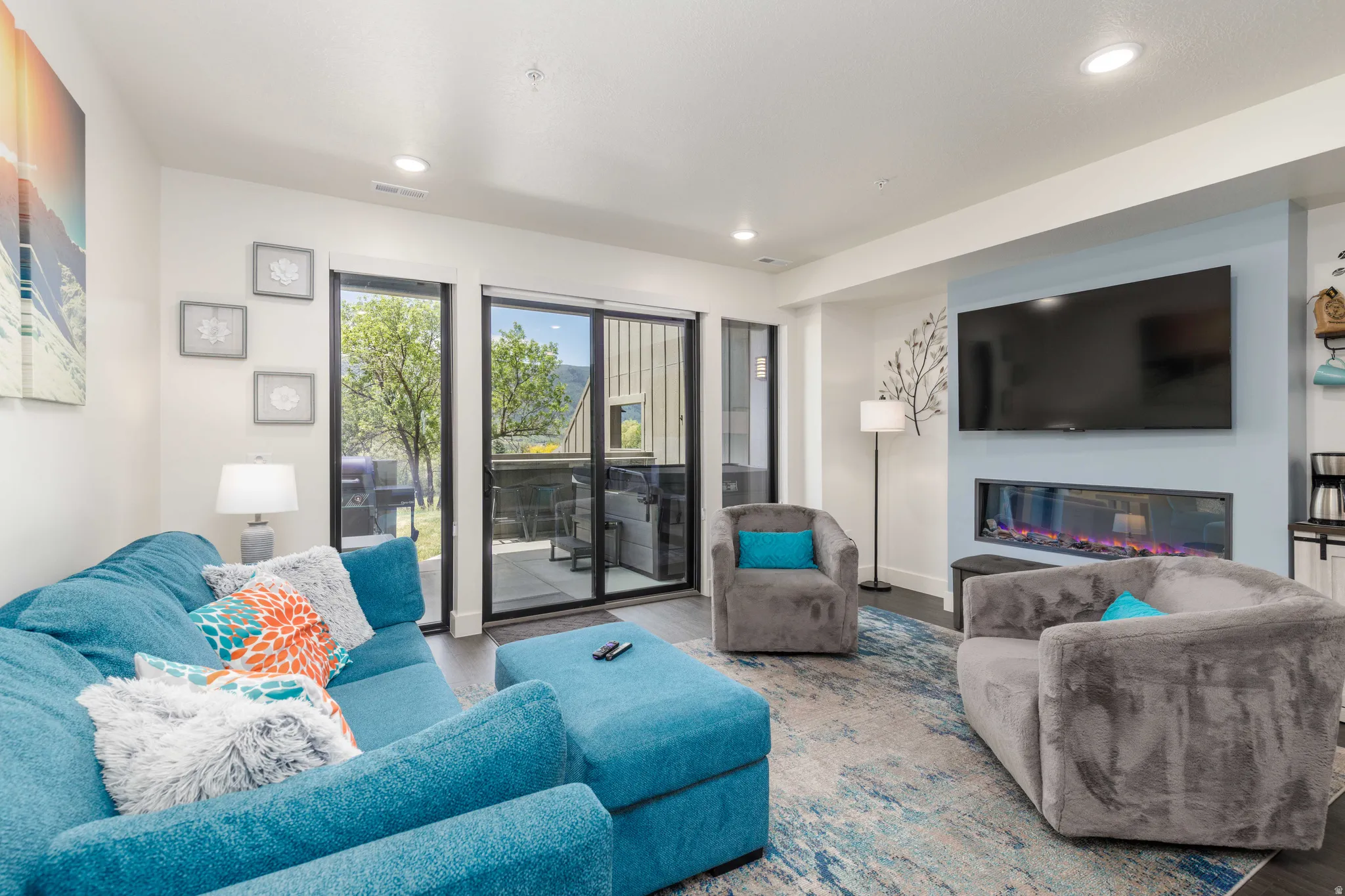 Open living area featuring wood-finish flooring, recessed lighting, and a contemporary linear fireplace