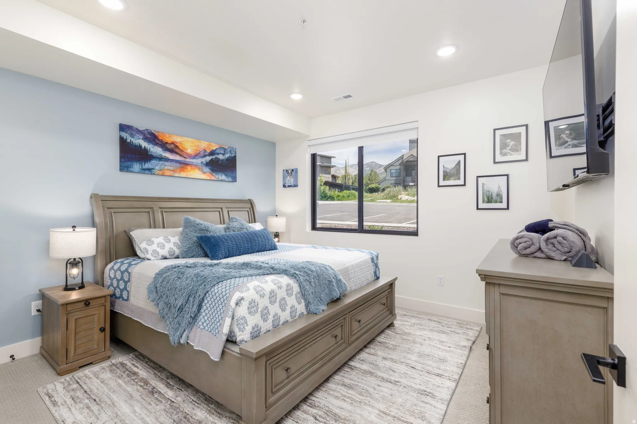 Spacious bedroom featuring light-colored carpeting, recessed lighting, and a large window with black framing