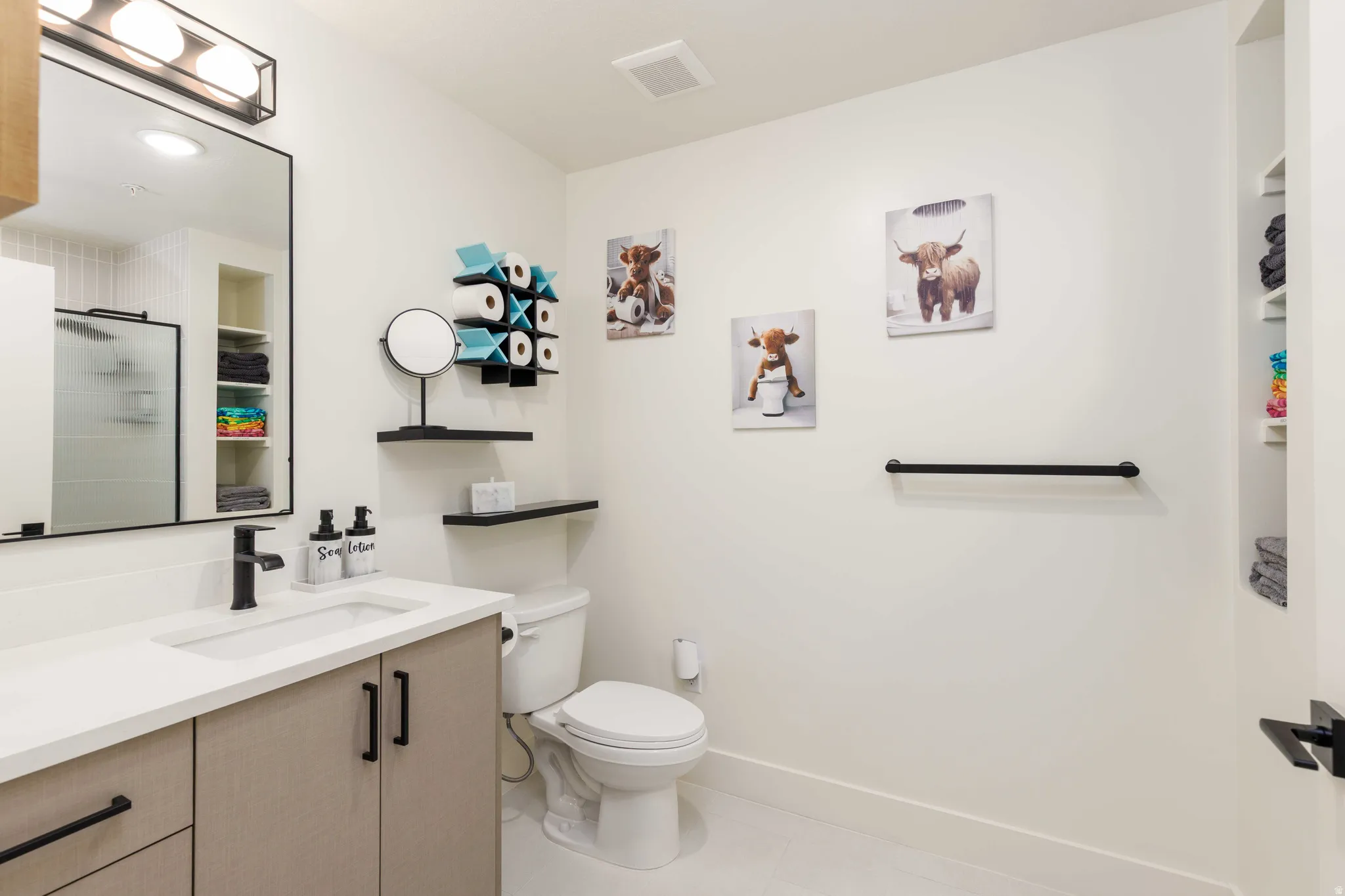 Bathroom featuring a vanity with light-toned cabinetry, a white countertop, and matte black hardware