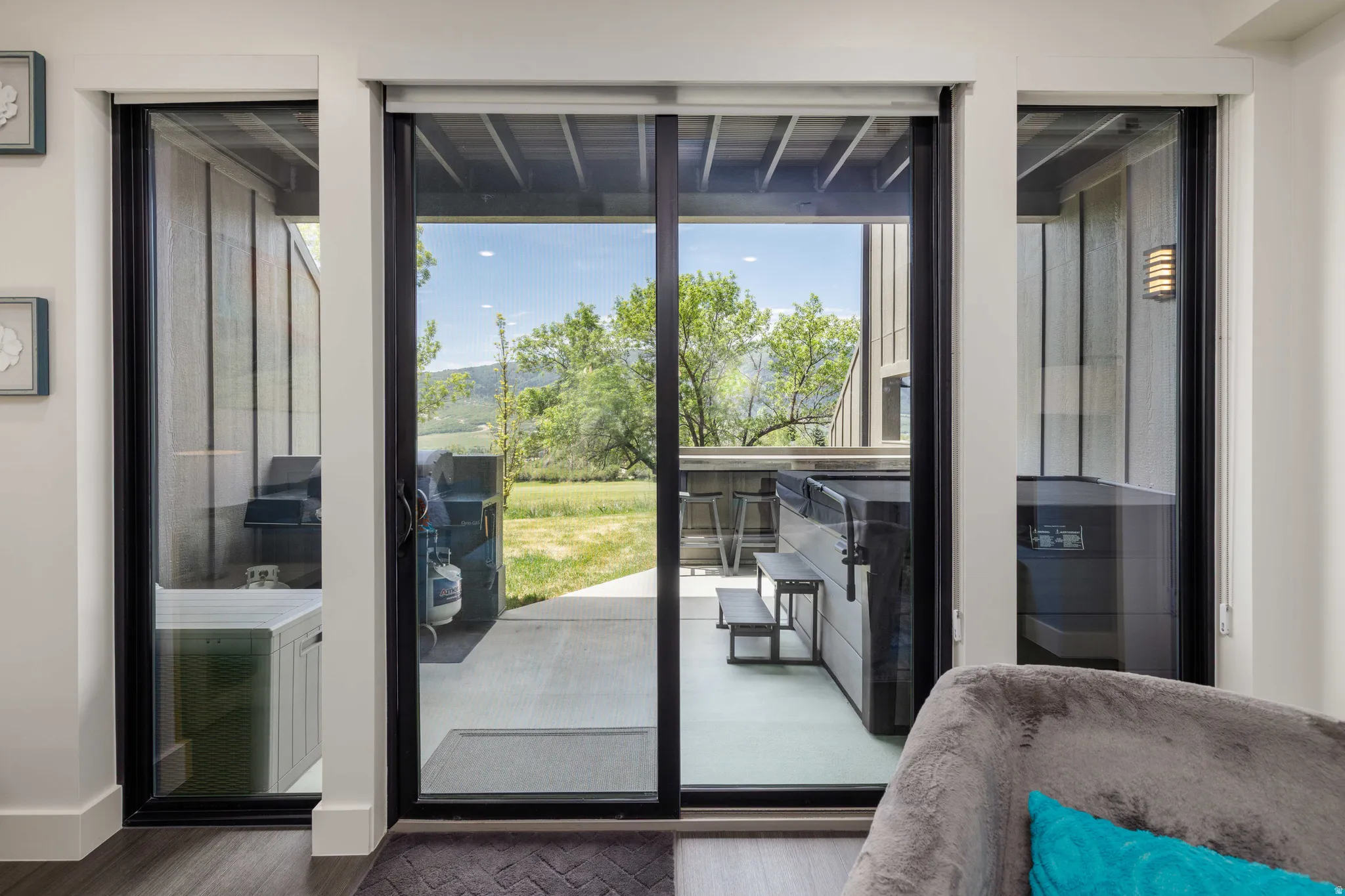 Patio access through sliding glass doors, featuring a hot tub, outdoor bar seating, and mountain scenery