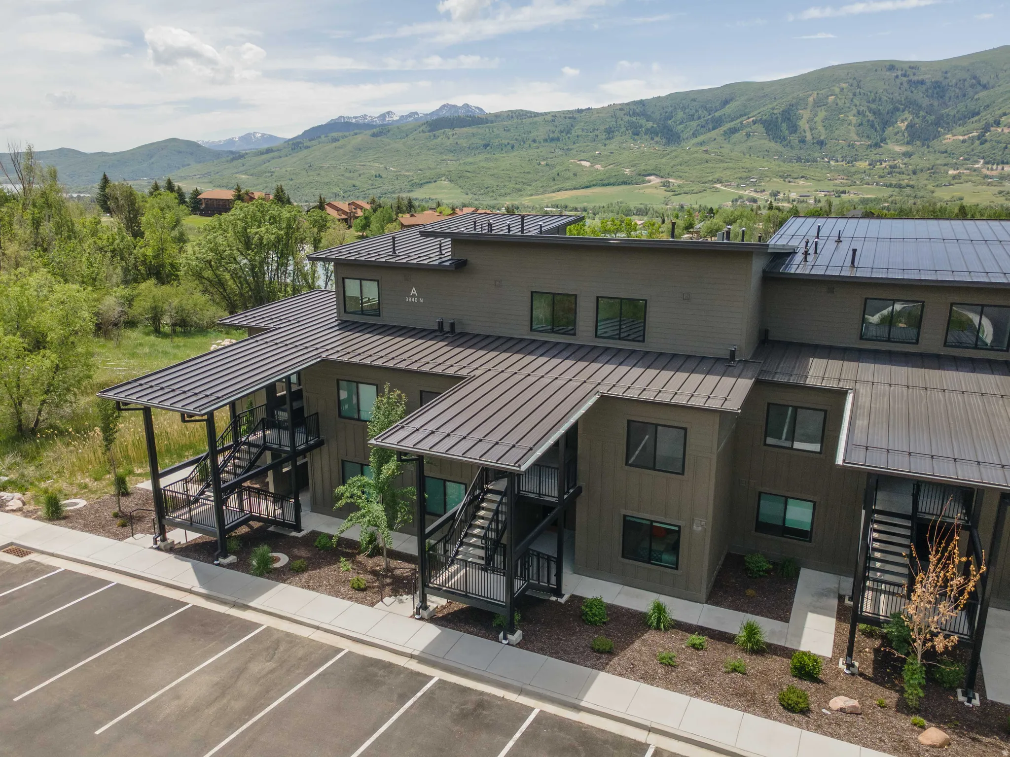 Modern multi-story building featuring dark siding and black metal roofs