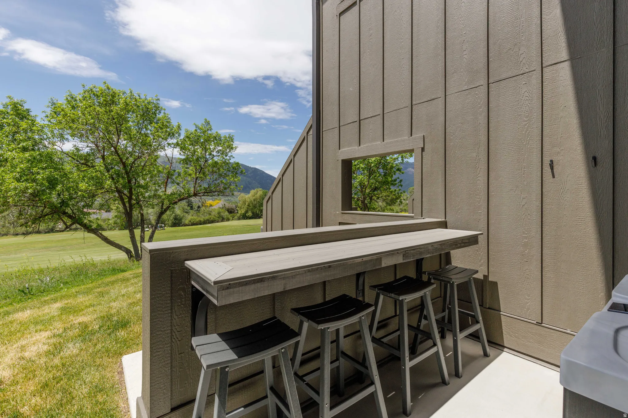 Outdoor bar area featuring a pass-through window and a composite countertop