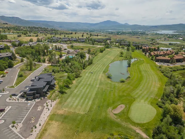 Expansive golf course setting featuring a green, sand trap, and water hazard