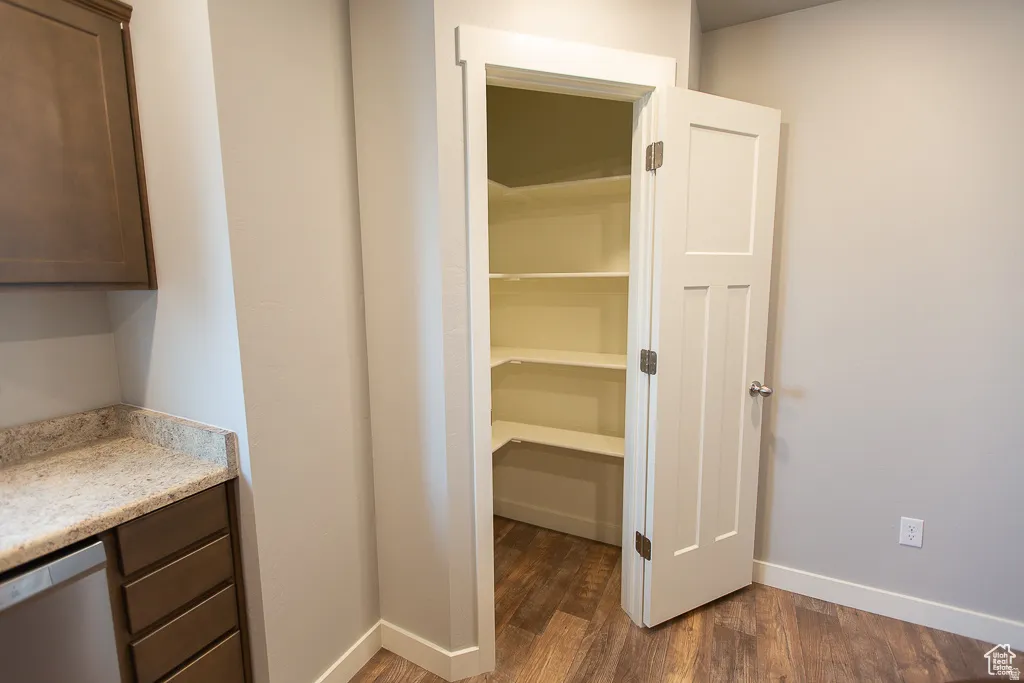 Walk-in pantry featuring multiple white shelves and wood-finish flooring