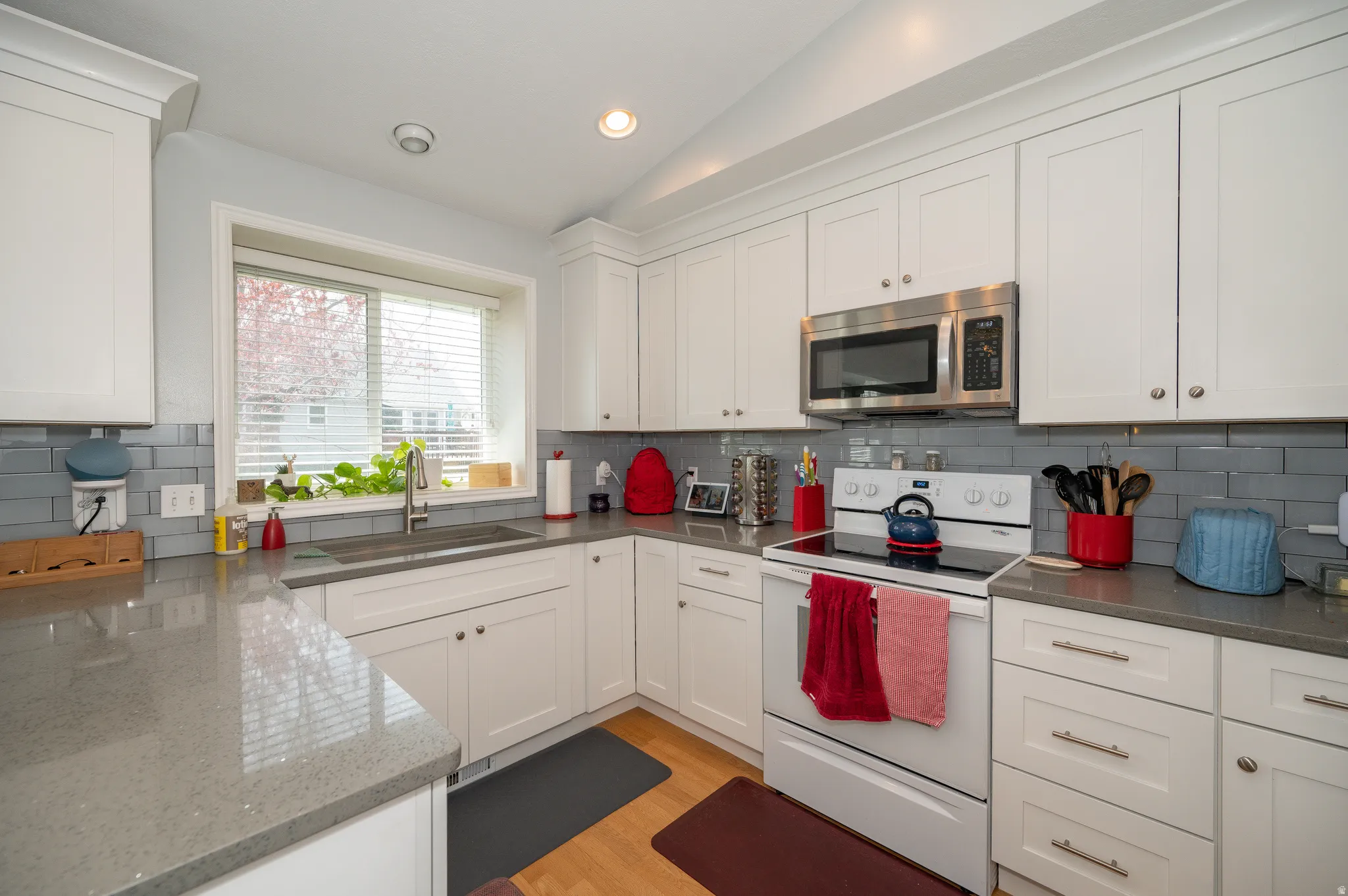 Kitchen featuring white cabinetry, gray subway tile backsplash, light wood-finish flooring, and recessed lighting
